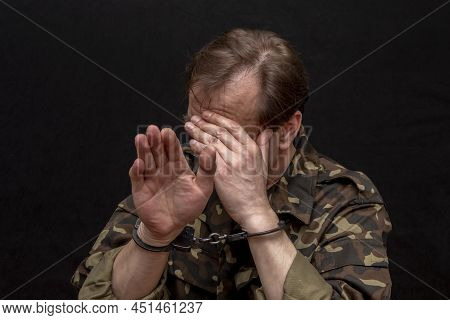 A Military Soldier Or Officer In Handcuffs On A Dark Background. War Criminal, Criminal Liability Of