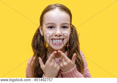 Girl Child Shows The First Molar And Smiles On A Yellow Background. The First Molar In A Child's Lif