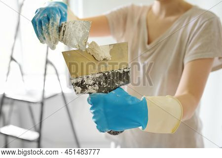 Young Female Worker Preparing Putty For The Wall Repair. Close-up View Of Spreading Plaster On Metal