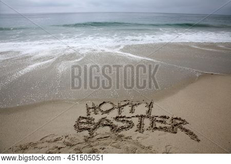 Hoppy Easter. The words HOPPY EASTER written in the sand by the ocean. Easter Sunday is a day to celebrate at the beach or anywhere you like. Hoppy Easter to all. 