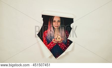Woman With Toy House Looking Through Hole In Paper. Female With Afro Braids And Miniature Wooden Hou