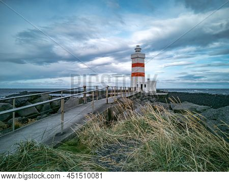 Lighthouse And Track Over The Breakwater With Rouch Ocean