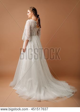 Beautiful Blonde Bride With Natural Looking Hairdo. White Wedding Dress With Feather
Print, Rear Vie