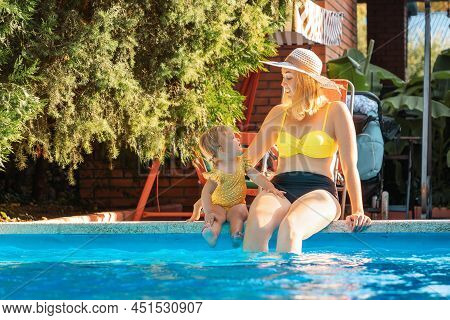 Summer Vacation. Happy Caucasian Young Mother With A Her Lettle Daughter Is Sitting On The Edge Of T