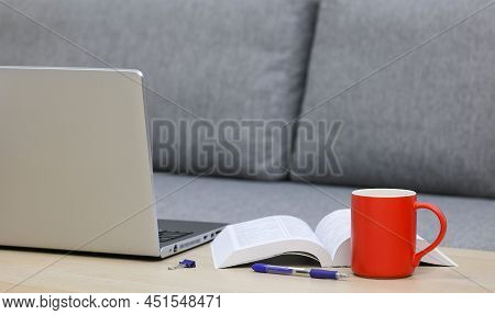 Coffee Cup, Laptop And A Book On A Table Near The Sofa
