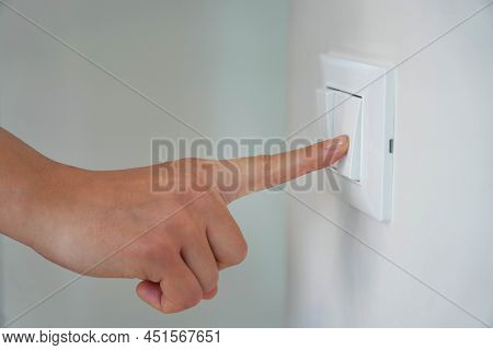 Wastage Of Energy. Female Finger Is Turn Off On Lighting Switch.