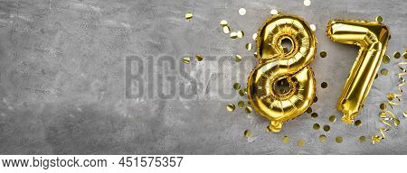 Yellow Foil Balloon Number, Number Eighty-seven On A Concrete Background. Greeting Card With The Ins