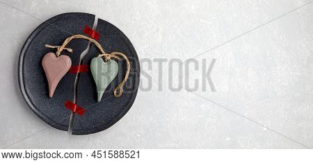 A Broken Plate Is Glued With Red Sticky Tape And Two Decorative Wooden Hearts On A Light Concrete Ta