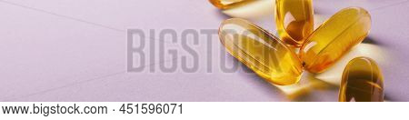 Fish Oil. Yellow Softgels Or Capsules Lie On A Pink Surface. Vitamins And A Healthy Lifestyle. Banne