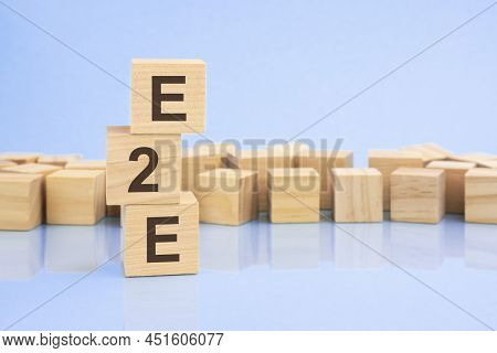 On A Bright Pale Lilac Background, Light Wooden Blocks And Cubes With The Text E2e. Cubes Is Reflect