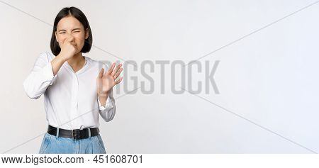 Disgusted Asian Girl Close Nose And Showing Rejection Gesture, Digusting Bad Smell, Standing Over Wh