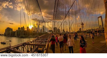 Tourist Enjoying The Twilight Skyline With Sunset Over New York City From The Brooklyn Bridge As Tra