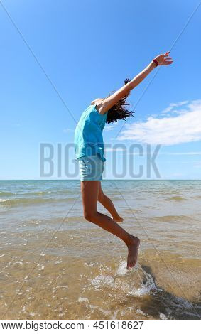 Young Girls Rejoices By Making Another Jump By The Sea With Their Arms Towards The Sky And Bare Feet