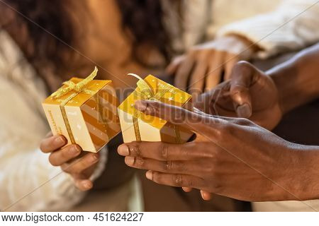 A Happy Couple Of Mulattoes Exchange Gifts With Each Other. Celebrating Joint Family Events