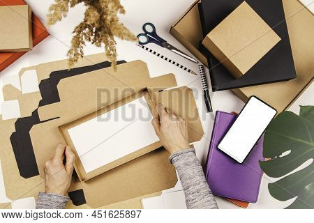Top View To Woman Hands Folding Paper Package Box On The Table. Startup Small Business Freelance Wor