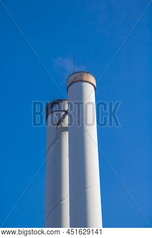Chimneys Of A Wood Pellet Power Plant For Local Heating Supply In Front Of Blue Sky