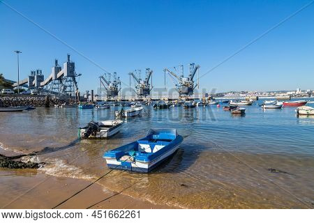 Trafaria; Portugal - March 01; 2022: Deep water terminal and silo for grain, derived products and oleaginous products in Trafaria, Portugal with fishing boats near the beach
