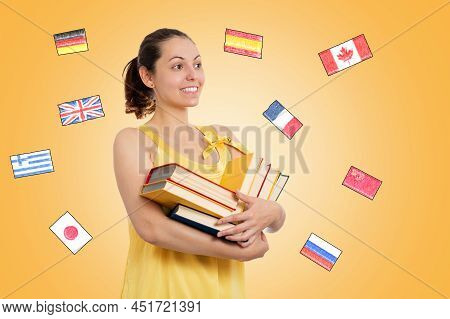 World Book Day. A Young Smiling Female Student In A Yellow Dress Holds A Stack Of Books. Yellow Back