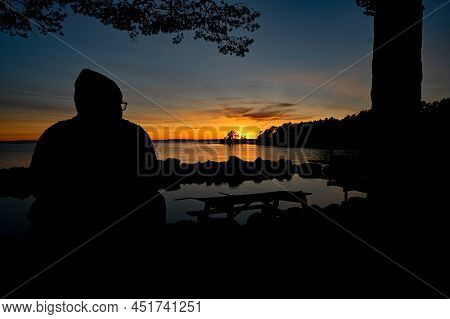Man Sitting Overlooking Sunset Over Lake Vattern