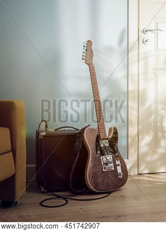 Electric Guitar And Amplifier Standing On The Floor Between Sofa And Door In Sunlight From The Windo