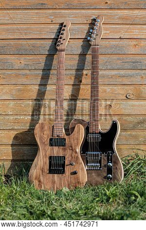 Electric Guitars Are Leaned Against A Wooden Wall Outside