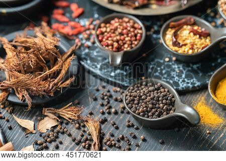 Food And Ingredent Concept. Closeup Of Spoon Of Black Pepper With Other Spices And Herbs On Wooden T