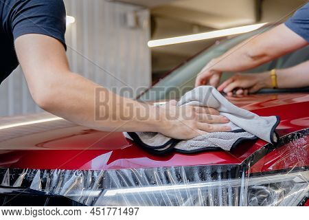 Concept Transparent Protection For Paint. Process Of Pasting Hood Of Red Car With Protective Vinyl F