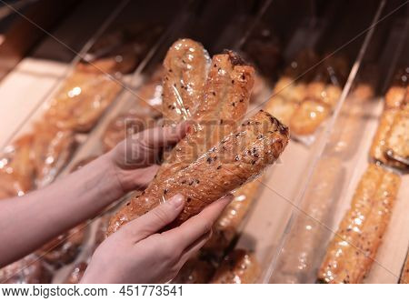 A Woman Holds A Rollini In Her Hands At The Supermarket Counter.