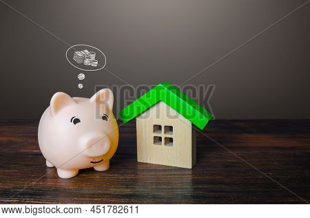 Pig Piggy Bank Dreams Of Making Money By Selling A House. Savings And Economy On Utilities Bills, En