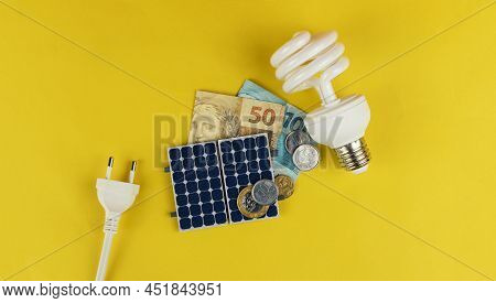 Photovoltaic Panel , Money And Plug Wire Isolated On Yellow Background. Olar Panel With Varied Value