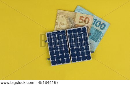 Photovoltaic Panel , Money And Plug Wire Isolated On Yellow Background. Olar Panel With Varied Value