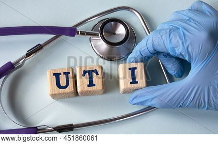 A Hand In A Medical Glove Puts Cubes With The Abbreviation Uti (urinary Tract Infection) On The Back
