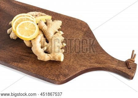 Fresh Ginger Roots With Sliced Lemon Slices Lie On A Wooden Brown Cutting Board.
