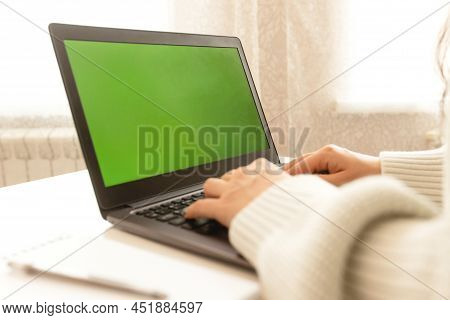 A Girl Works At Home At A Dask With A Laptop And Smiles.