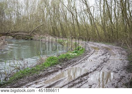Extremely Muddy Trail After Rain With Messy Tire Tracks Next To River Cole In Whelford, England
