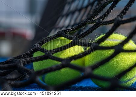 Selective Approach, Two Paddle Tennis Balls Behind The Net Of A Blue Paddle Tennis Court