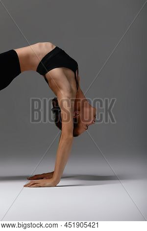 Beautiful Flexible Young Gymnast Woman In Black Leotard Working Out, Stretching, Doing Backbend Exer