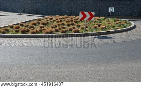Roundabout Of Gray Granite Cubes Closer To The Center. Beveled Concrete Curbs With Flowers And Grass