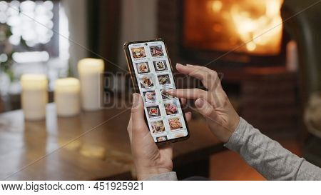 Ordering food using a smartphone at home. A woman selects estaurant food in the internet menu of a gourmet restaraunt using an application on a smartphone.