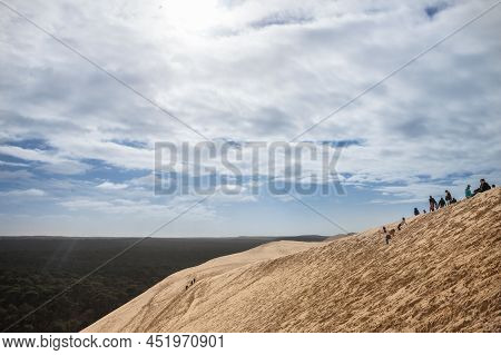 Pilat, France - February 22, 2022: Group Of Tourists Climbing In Crowd The Sandy Slopes Of The Pilat