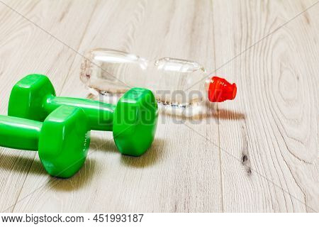 Green Dumbbells For Fitness And A Bottle Of Waterl On The Floor.
