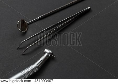 Head Of High-speed Dental Handpiece With Bur, A Metal Mirror And A Tweezers On The Black Background.