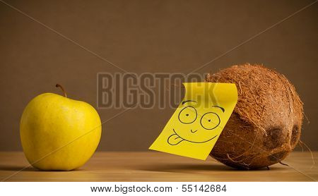 Coconut with sticky post-it note gesturing at apple