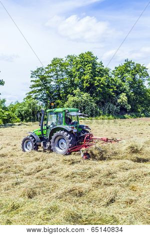 Tractor In Meadow Making Hay