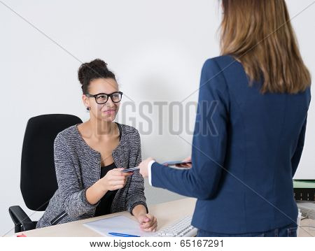 Woman Hands Over A Document To Another Woman