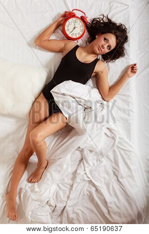 Sexy Lazy Girl Lying With Red Alarm Clock On Bed