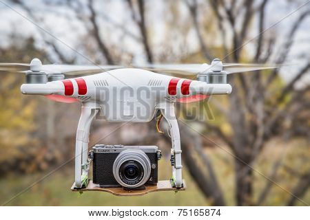 FORT COLLINS, CO, USA, November 2, 2014:  Airborne radio controlled DJI Phantom 2 quadcopter drone flying with  the Panasonic Lumix GM1 camera mounted on a home made platform, blurred tree background.