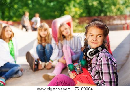 Girl holds skateboard wearing headphones