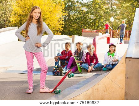 Smiling girl in with skateboard and her friends