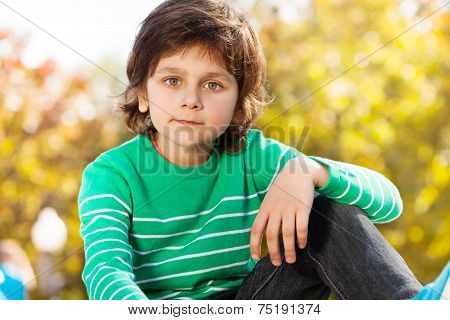 Cute boy in green sweater with arm on his knee